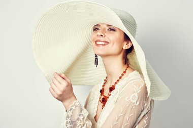 Zarif, dantelli bir elbise ve kameraya gülümseyen geniş kenarlı bir şapkayla büyüleyici bir genç kadının portresi. Moda fotoğrafı, yaz tarzı. Mutluluk.