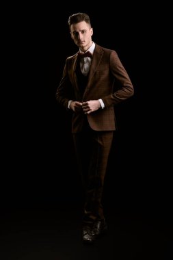 Full length portrait of a handsome man in elegant classic suit and bow tie on a black background. Business style. Men's fashion. clipart