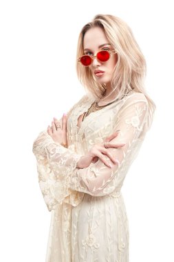 Yaz stili. Açık beyaz dantelli elbise ve güneş gözlüğü takan sarışın güzel bir kızın portresi. Beyaz arkaplanda stüdyo portresi.