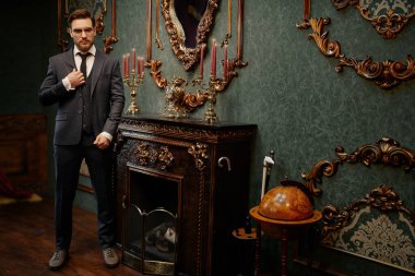 Yakışıklı beyefendi tüvit takım elbise içinde poz veriyor ve gözlük takıyor. Lüks bir yaşam tarzı. Eski tarz. Tam uzunluk.