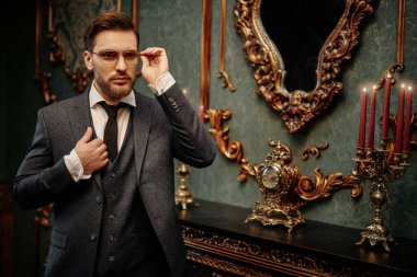 Yakışıklı beyefendi tüvit takım elbise içinde poz veriyor ve gözlük takıyor. Lüks bir yaşam tarzı. Klasik stil. 