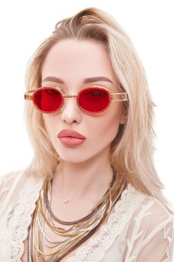 Yaz stili. Açık beyaz dantelli elbise ve güneş gözlüğü takan sarışın güzel bir kızın portresi. Beyaz arkaplanda stüdyo portresi.