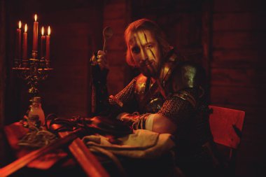 Zırhlı ve silahlı bir ortaçağ savaşçısı handa dinleniyor. Sahne portresi. Büyücü adam..