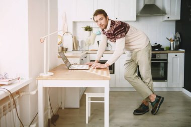 Evde dizüstü bilgisayarı olan bir adamın portresi. Sıradan bahar modası, erkekler için aletler..