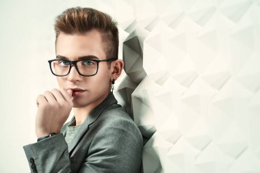 Takım elbiseli ve gözlüklü zeki bir gencin portresi. Stüdyo çekimi. Erkeklerin güzelliği.