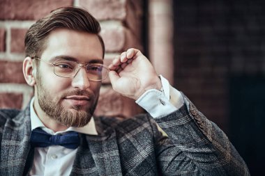 Sakallı, bıyıklı, şık takım elbiseli ve gözlüklü yakışıklı bir beyefendinin portresi. Erkek güzelliği, moda. İş adamı portresi. Erkekler için optik.