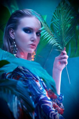 Palmiye yapraklarının arasında ıslak saçlı güzel bir tropikal kadının portresi. Güzellik, moda ve kozmetik konsepti. Tropikal ülkelerde tatil.