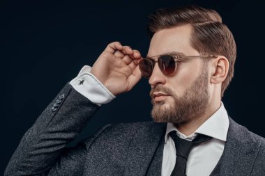 Siyah arka planda takım elbiseli ve gözlüklü yakışıklı bir iş adamının portresi. Erkek güzelliği, moda. Erkekler için optik. Boşluğu kopyala. 