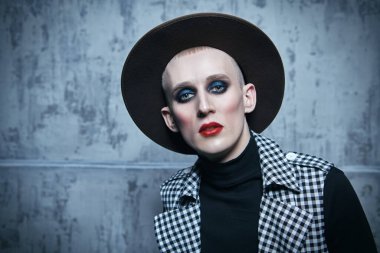 Kadın makyajı ve giysisi ve grunge arka planında olan genç bir adamın portresi. 