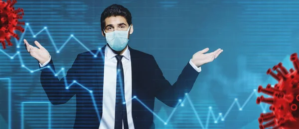 Coronavirus and business. A businessman in a medical mask makes a helpless gesture against the background of a coronavirus and stock charts. Copy space.