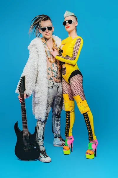 A full length portrait of two cool young punk people posing in the studio. Modern punk fashion, rock band.