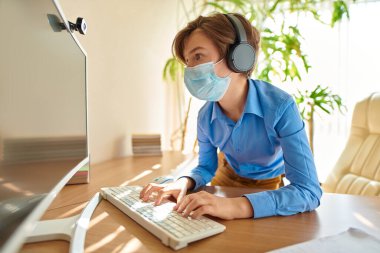 Coronavirus ve yaşam. Erkek öğrenci COVID-19 yüzünden karantina nedeniyle evde kalıp öğreniyor. Sosyal medya ağları aracılığıyla iletişim.