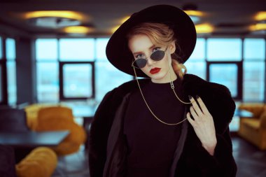 Siyah kürklü, zarif elbisesi ve iç çamaşırlı güneş gözlüklü şık bir kadın. Güzellik, moda. Optik ve gözlük.