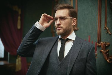 Zarif takım elbiseli yakışıklı zengin adam lüks dairelerde duruyor. İş adamı portresi. Erkek modası..