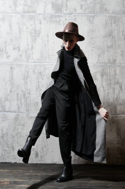 Arka planda kadın makyajı ve giysisi olan genç bir adamın tam boy portresi. Avangart.