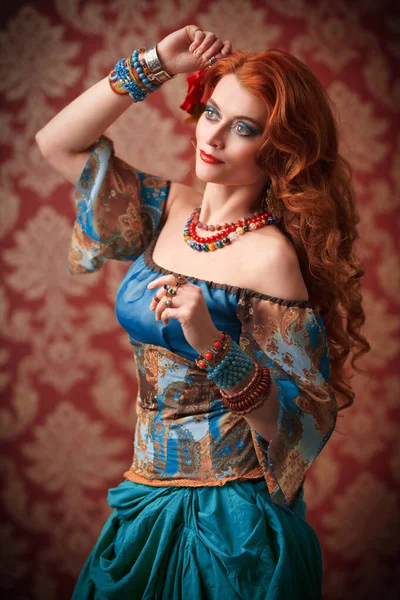 Beautiful red-haired gypsy woman is dancing. National gypsy costume, ethnic. Make-up and hairstyle.