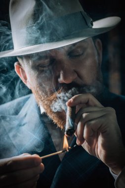 Klasik iç mekanda poz veren purolu düşünceli bir adamın portresi. Erkek güzelliği, moda, stil.