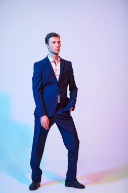 Stüdyoda resmi takım elbiseli yakışıklı bir gencin tam boy portresi. Erkek modası.