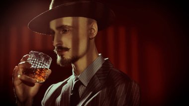 Zarif klasik takım elbiseli yakışıklı bir adamın viski içen portresi. Retro tarzı. Lüks bir yaşam tarzı. Erkek güzelliği, moda.