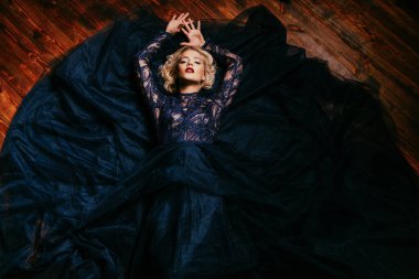 Güzel bir sarışın Bayan yerde yatıyor. Gece elbisesi. Moda, güzellik.