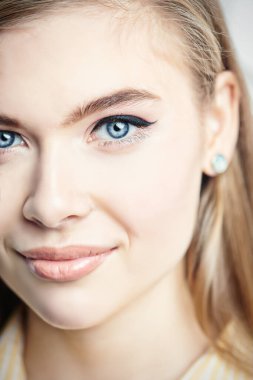 Kameraya gülümseyen doğal makyajlı mutlu bir genç kızın yakın plan portresi. Stüdyo güzellik portresi.