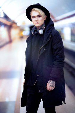 Yeraltında yürüyen sarışın bir gencin portresi. Sıradan moda, güzellik..