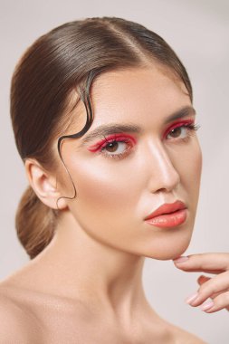 Makyaj ve kozmetik konsepti. Parlak makyajlı ve gözlerinde kırmızı oklar olan güzel bir kızın portresi. Güzellik, moda.