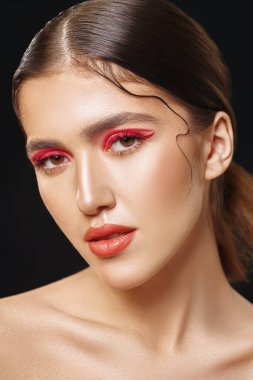 Makyaj ve kozmetik konsepti. Parlak makyajlı ve gözlerinde kırmızı oklar olan güzel bir kızın portresi. Güzellik, moda. Siyah arkaplan. 