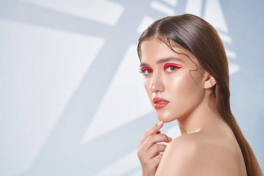 Makyaj ve kozmetik konsepti. Parlak makyajlı ve gözlerinde kırmızı oklar olan güzel bir kızın portresi. Güzellik, moda. Boşluğu kopyala.