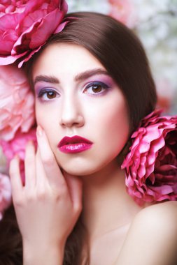 Güzel bir manken. Mor eflatun makyajlı ve saçlarında şakayık çiçekleri var. Moda ve çiçekler. Makyaj, saç stili. Parfüm konsepti.