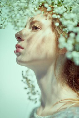 Yüzünde güzel çiller ve beyaz bir arka planda çingene çelengi olan güzel bir genç kız. Bahar ve yazın ilham kaynağı. Parfüm, kozmetik konsepti.