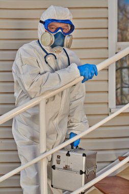 Coronavirus konsepti. Koruyucu takım elbiseli, gözlüklü ve solunum maskeli acil servis doktorunun portresi..