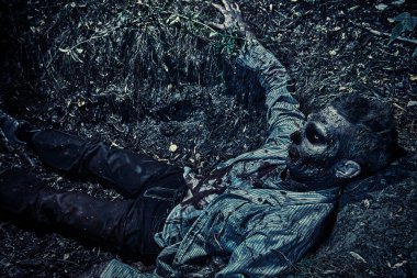 Gece mezarlığındaki mezarda oturan zombi. Cadılar Bayramı. Korkunç..