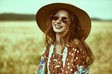 Buğday tarlasında modern bir hippi kızın portresi. Bohem stili.