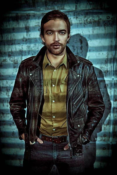 Portrait of a handsome brutal man in leather jacket on a grunge background.