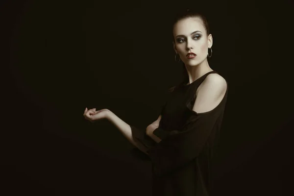 A portrait of a fashionable young lady in black posing in the studio. Style, beauty.