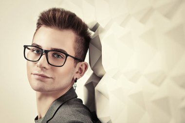Takım elbiseli ve gözlüklü zeki bir gencin portresi. Stüdyo çekimi. Erkeklerin güzelliği.