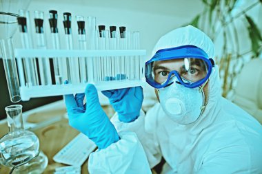 COVID-19 ve ilaç. Bir doktor, mikrobiyolog, koruyucu kıyafetli bir bilim adamı laboratuarda araştırma yapıyor.. 