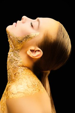 Güzellik, moda altın kavramı. Siyah arka planda altın tenli ve altın makyajlı güzel bir kız modelinin profil portresi. Mücevherler. Kozmetik ve güzellik hizmetleri.