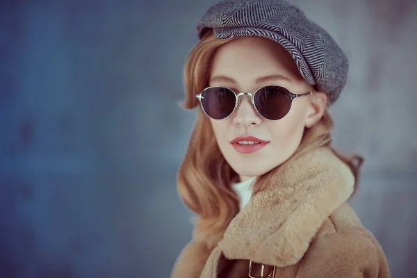 Romantic young woman with natural makeup and beautiful wavy blonde hair wearing outerwear and trendy sunglasses. Beauty, fashion concept. Optics and eyewear style.