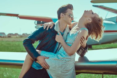 Yakışıklı pilot uçuştan önce güzel kız arkadaşına sarılıyor. Havacılık ve aşk. 