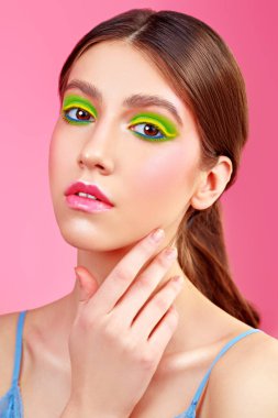 Makyaj ve makyaj malzemeleri. Pembe arka planda canlı renkli makyajlı güzel bir kızın yakın plan portresi..