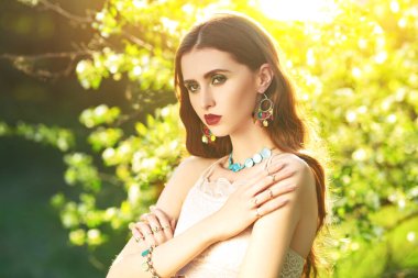 Yeşil bir ağacın dalları arasında romantik esmer bir kızın portresi. Bir pınarın güzelliği. Makyaj ve kozmetik.