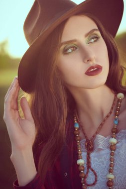 Gün batımında güzel bir manzaranın arka planında romantik esmer bir kızın portresi. Yaz tatili. Modern gençlik yaşam tarzı.