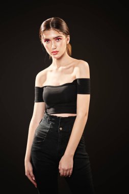 Çekici esmer bir kızın portresi parlak makyajlı siyah bir arka planda stüdyoda poz veriyor. Güzellik, moda. Kırmızı oklarla modern makyaj..