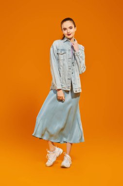 Stüdyoda sarı arka planda poz veren kot elbiseli manken. Moda, yeni yaz tarzı. Gülümseyen genç bir kızın tam boy portresi..