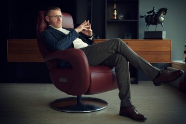 Zarif takım elbiseli, gözlüklü, deri koltukta oturan saygıdeğer orta yaşlı bir işadamının portresi önemli bir soru üzerine kafa yoruyor. Başarı ve liderlik.