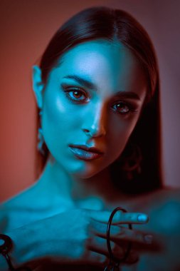 Güzellik, moda konsepti. Karmaşık renklerde poz veren çekici esmer bir kızın portresi. Makyaj, makyaj malzemeleri, mücevherler. Stüdyo çekimi.