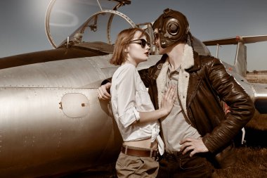 Yakışıklı pilot uçuştan önce güzel kız arkadaşına sarılıyor. Havacılık ve aşk. 