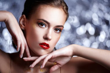 Makyaj ve makyaj malzemeleri. Işıl ışıl gümüş bir arka planda altın makyajlı muhteşem bir genç kadının portresi. Parti biçimi.